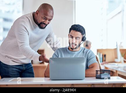 Its quite a simple process. Shot of a businessman teaching his staff member in a call center. Stock Photo