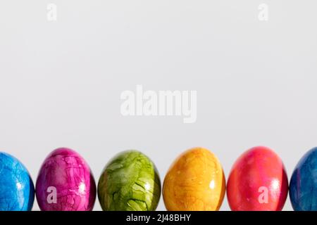 Many Easter eggs arranged in one row on a white background. Easter. Stock Photo
