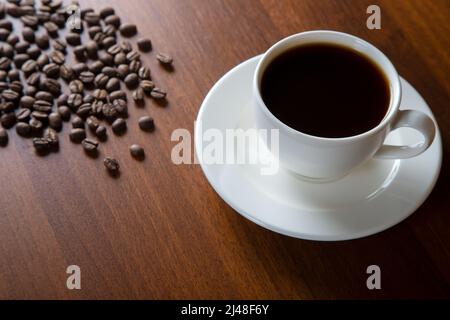 Coffee beans with a cup of coffee on wooden background, top view Stock Photo