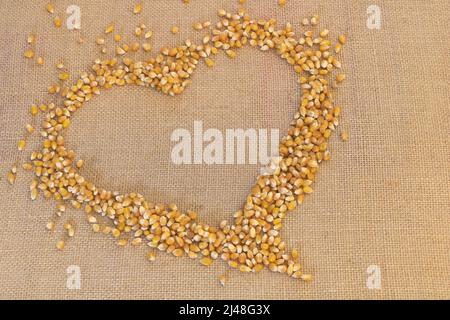 Raw heart-shaped popcorn grains on hessian background Stock Photo