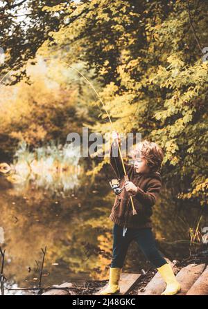 Photo of kid pulling rod while fishing on weekend. Stock Photo