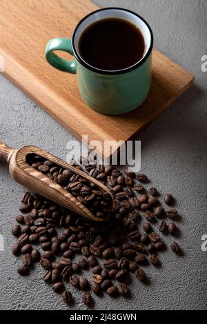 Green cup of coffee with coffee beans on concrete background Stock Photo