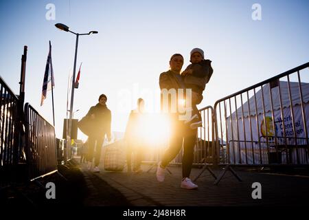 Przemysl, Poland. 13th Apr, 2022. A family that fled Ukraine walks to a bus in the morning at the Medyka border crossing just across the Ukrainian border on the Polish side. Credit: Christoph Soeder/dpa/Alamy Live News Stock Photo