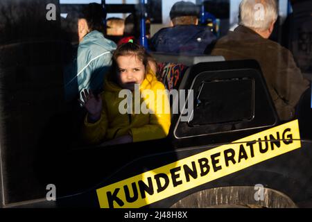 Przemysl, Poland. 13th Apr, 2022. A girl who fled Ukraine with family members waits in the morning at the Medyka border crossing, just across the Ukrainian border, on the Polish side, in a bus probably originating from Germany, for the onward journey. Credit: Christoph Soeder/dpa/Alamy Live News Stock Photo