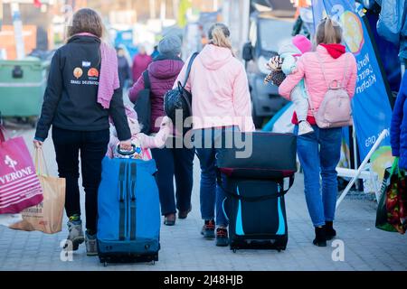 Przemysl, Poland. 13th Apr, 2022. Women and children who fled Ukraine are escorted by a volunteer (l) at the Medyka border crossing, just across the Ukrainian border, on the Polish side. Credit: Christoph Soeder/dpa/Alamy Live News Stock Photo