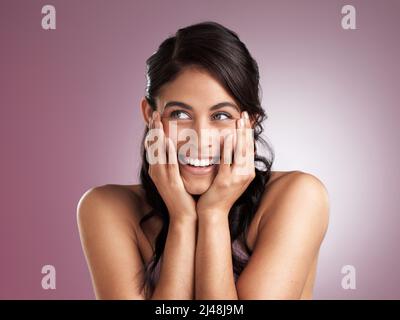 Dream big, stay focussed and make it happen. Shot of a beautiful young woman pondering with her hands rested her chin and face against a pink Stock Photo