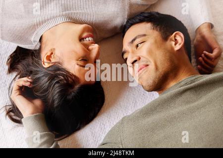 Nothing says holidays like a cheesy love. Shot of a young couple laying on the floor at home. Stock Photo