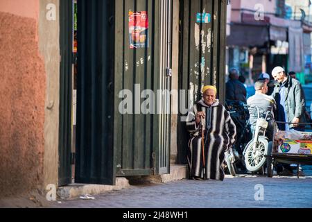 Marrakesh, Morocco -March 28, 2022: A typical street in the ancient Medina district of Marrakech. Photo contains local people doing various activities. Stock Photo