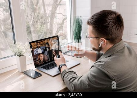 Back view portrait of happy businessman explaining the moments of a new project to colleagues on video meeting,sitting at the desk in home office.Styl Stock Photo