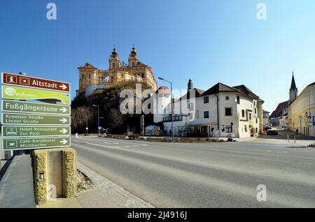 Melk, Austria - March 26, 2022: Impressive baroque Melk abbey on rock in UNESCO world heritage site of Danube Valley, board with information on the ol Stock Photo
