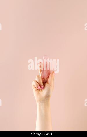 A woman holds a gouache jade massage scraper in her hand. Trendy beauty treatments. Copy space. Stock Photo