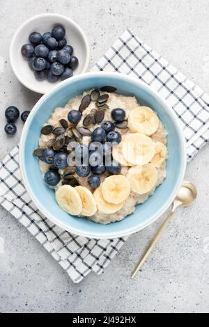Oatmeal bowl with blueberries, banana slices and pumpkin seeds. Top view. Healthy breakfast food for diet, weight loss, clean eating Stock Photo