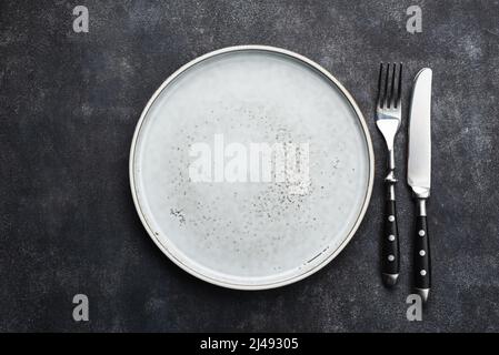 Empty ceramic plate and cutlery on black background. Top view copy space for design elements, text, templates Stock Photo