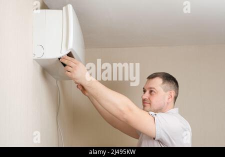 The air conditioner repairman repairs the air conditioner, cleans the filters from dust Stock Photo