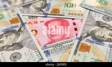 100 yuan banknote among 100 US dollar banknotes Stock Photo
