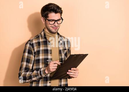 Portrait of attractive cheerful guy focused smart attorney lawyer writing checking document isolated over beige pastel color background Stock Photo