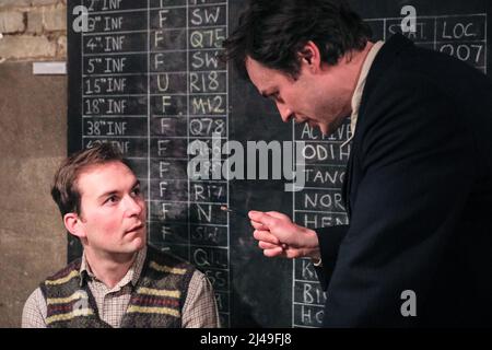 London, UK, 13th April 2022. Christopher Styles and Timothy Styles in an interrogation scene. Immersive theatre company Parabolic Theatre presents the remount of their successful 'Illicit Signals Bletchley'. Audiences can interact, walk around and work alongside famous figures from the Government Code and Cipher School at Bletchley Park to crack ENIGMA, while uncomfortable secrets closer to home threaten to be revealed. The show runs at Parabolic Theatre's newly launched immersive venue CRYPT starring Christopher Styles, Amelia Stephenson, Timothy Styles and Beth Jay. Stock Photo