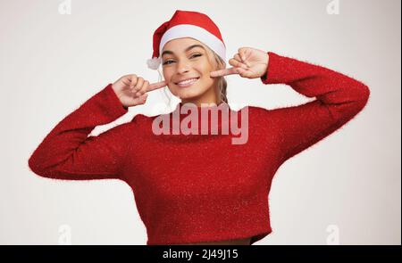 Santa Claus is anyone who loves another. Studio shot of a young woman posing against a grey background. Stock Photo