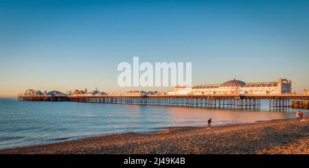 14 January 2022: Brighton, East Sussex, UK - Sunrise at Brighton Palace Pier, with people on beach. Stock Photo