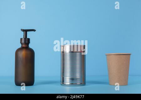 Recycling paper cups, tin products, glass. used products stand in a row for sorting on a blue background. Stock Photo