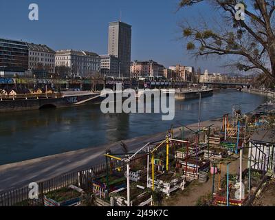 Beautiful view over canal Donaukanal in the downtown of Vienna, Austria with community garden on the riverbank and skyscraper Ringturm on sunny day. Stock Photo