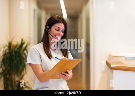 Smiling female medical worker taking notes on clipboard Stock Photo