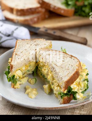 Egg salad sandwich with lettuce on whole grain bread cut in half on a plate Stock Photo
