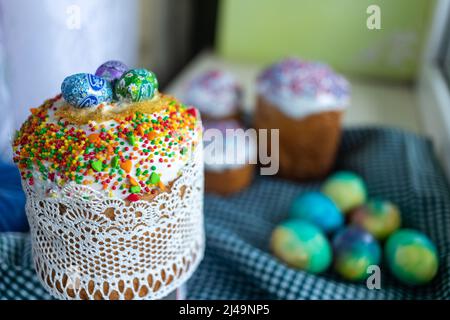 Easter cake with glace icing decoration and colored easter eggs on a holiday table Stock Photo