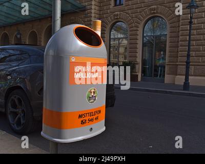 Closeup view of a grey and orange colored dustbin in the historic center of Vienna, Austria with funny slogan. Stock Photo