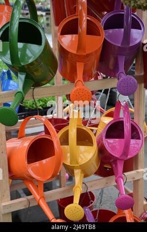 Colorful metal watering cans on display in garden store Stock Photo
