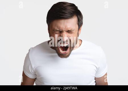 Mad Male Shouting Loudly In Anger With Eyes Closed, Studio Stock Photo