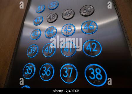 Close-up of blue glowing elevator buttons with Braille characters, numbers from the 35th floor to the 52nd floor Stock Photo