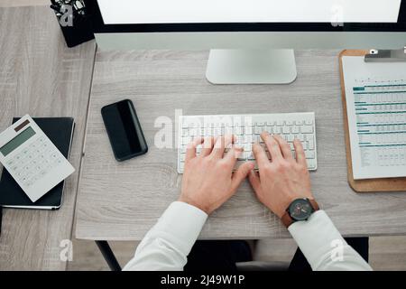 Working towards success. High angle shot of an unrecognisable businessman sitting alone in his office and using his keyboard. Stock Photo