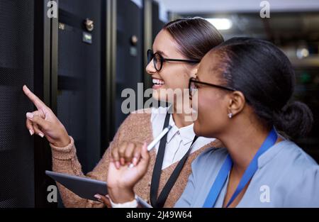 Looks like its all sorted. Cropped shot of two attractive young female computer programmers working together in a server room. Stock Photo