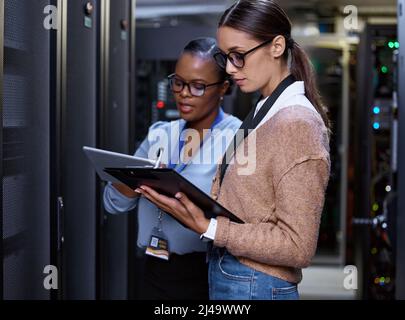 What speeds are you getting. Cropped shot of two attractive young female computer programmers working together in a server room. Stock Photo