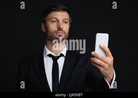 Businessman Using Phone Texting Or Using Mobile Application, Black Background Stock Photo