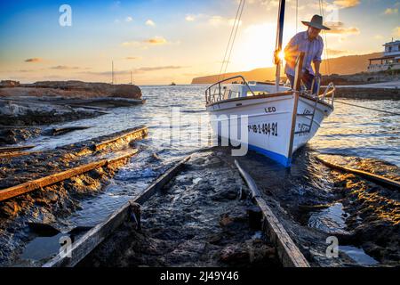 Fisherman in a boat in es Caló de San Agustí boat jetty port in Formentera island wooden boat railways in Formentera Balearic islands Spain Stock Photo