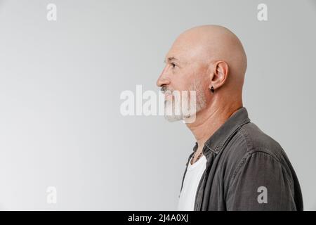 Bald european man with beard looking aside while posing in profile isolated over white background Stock Photo
