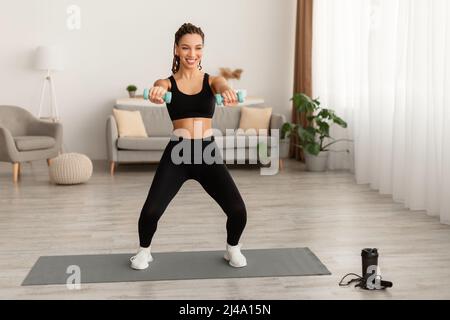 Cheerful Black Female Doing Squats Exercise Holding Dumbbells Training Indoor Stock Photo