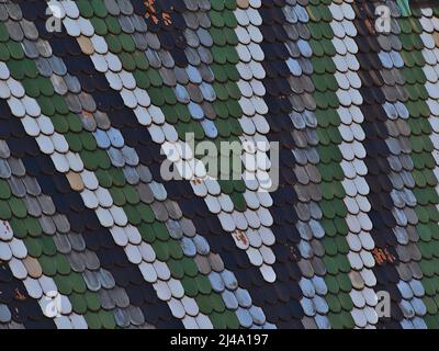 Beautiful closeup view of famous ornate roof of cathedral Stephansdom in the old center of city Vienna, Austria with texture of multi-colored tiles. Stock Photo