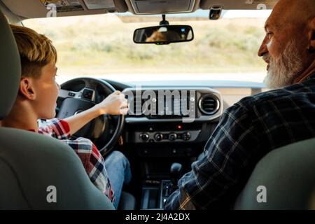 Happy middle aged father and his preschooler son sitting in a car driving car back view Stock Photo