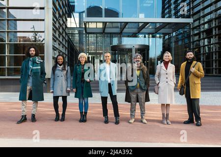 Diverse coworkers standing on street with glass walls Stock Photo