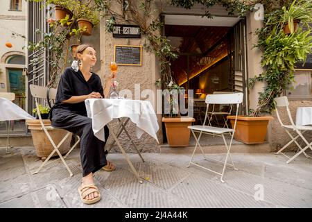 Woman sitting with wine at italian restaurant on cozy street Stock Photo