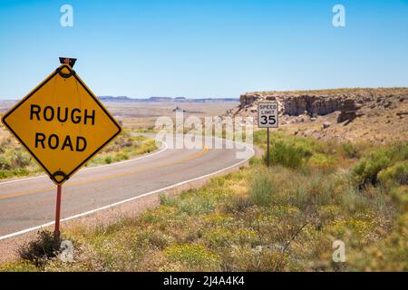 A 'rough road' sign on a bending stretch of desert highway in the Southwestern United States Stock Photo