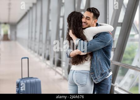 Long Awaited Meet. Happy Arab Man Hugging Girlfriend At Airport After Arrival Stock Photo