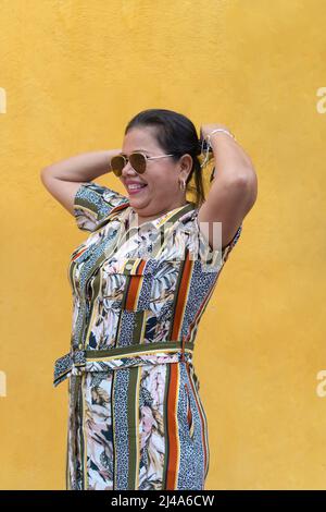 Hispanic woman poses walking outdoors on the street, fixing her hair, smiling Stock Photo
