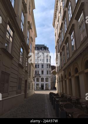 Beautiful view of empty narrow alley in the historic downtown of Vienna, Austria on sunny day with shadow between old buildings with ornate facades. Stock Photo