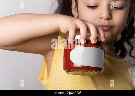 Little girl holding a homemade tomato paste in hand, editable mock-up series template ready for your design. label selection path included. Stock Photo