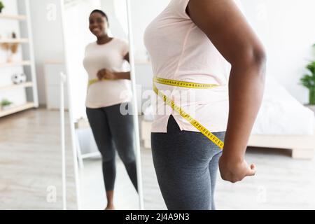 Woman measuring her waist with centimeter tape at home Stock Photo - Alamy