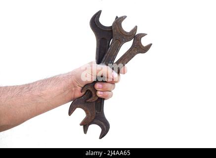 Male hand holding three old rusty spanners isolated on white background Stock Photo